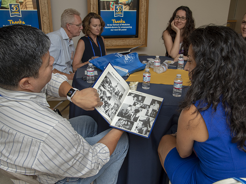 Joe Gantan, Amy Culver, Estela Hernandez and other members of the Class of 1998 reminisce over yearbooks.