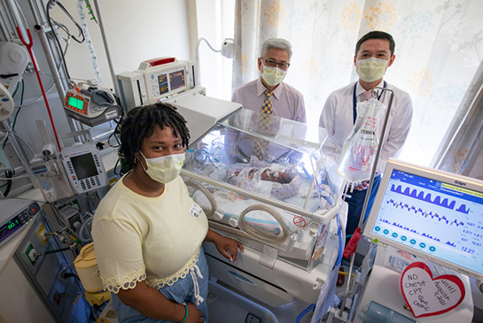 Infant Cedric in hospital bed surrounded by health care workers
