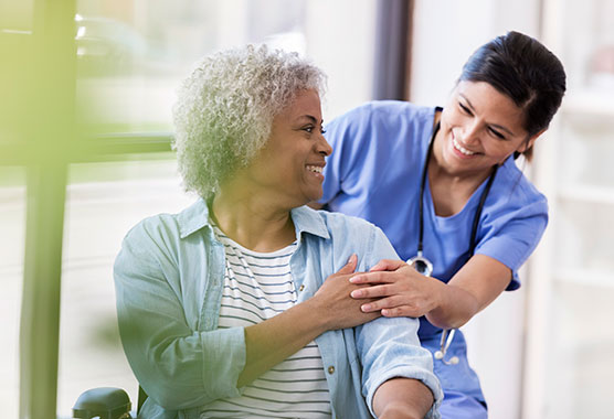 Older female patient smiling over her shoulder at her female nurse 