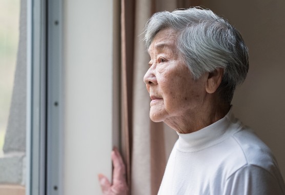 Older woman looking serious as she watches out a window