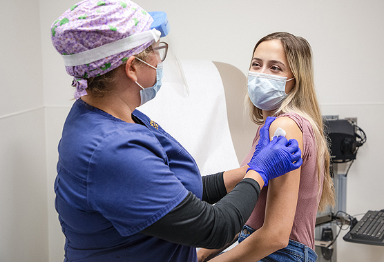 Female nurse cleaning the arm of a female patient in preparation for a vaccine 