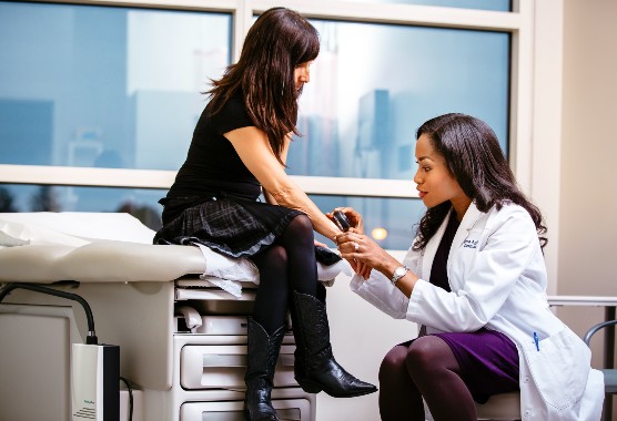 Female dermatologist examining female patient’s skin in clinic