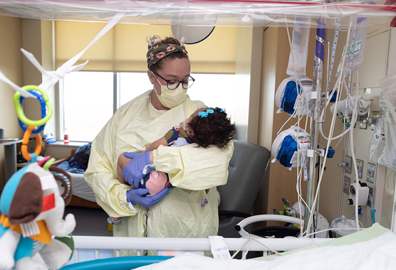 Nurse holding a small child in the PICU