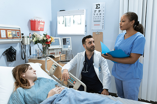 Female patient in a hospital bed talking to two providers 
