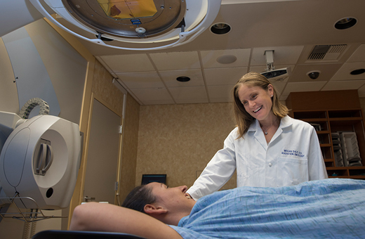 Female provider smiling down at a female patient lying on a table before a scan