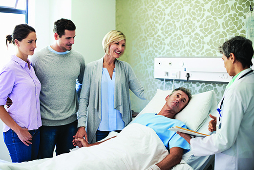 Doctor talking to a mature man in a hospital bed surrounded by his family