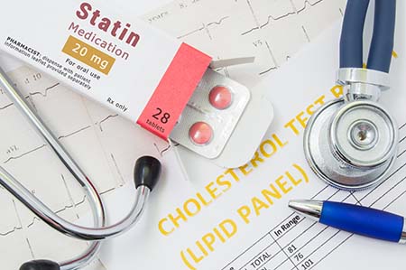 opened package of statin drug tablets near a stethoscope