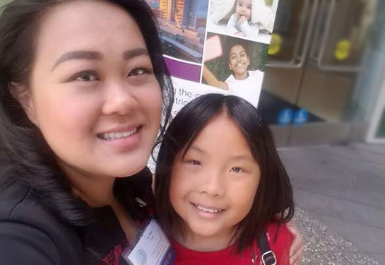 Annabelle (right) and mom (left) in front of a Pediatric Heart Center sign