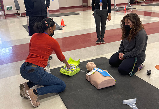 Four people practice CPR on a dummy. 