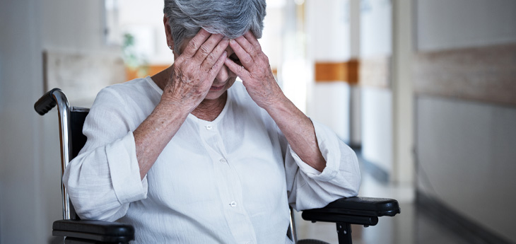 Senior woman in a wheelchair sitting with her hands over her eyes