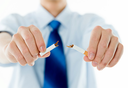 Hands against a background of a white shirt and blue tie breaking a cigarette in half
