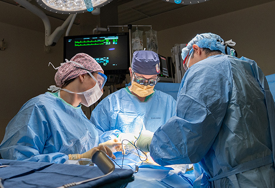 Dr. Neal Mineyev in the operating room performing a living donor kidney transplant surgery, working with the recipient patient.