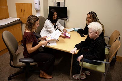 Mother and adolescent genomic patient meet with doctor and counselor.