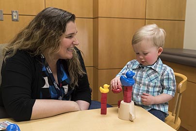 Doctor tests very young male pediatric patient with blocks and puzzle.