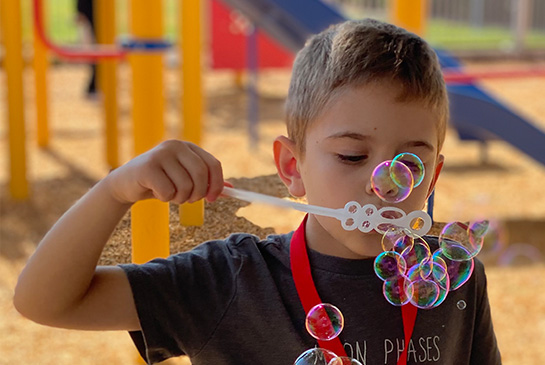 boy blowing bubbles on a playground