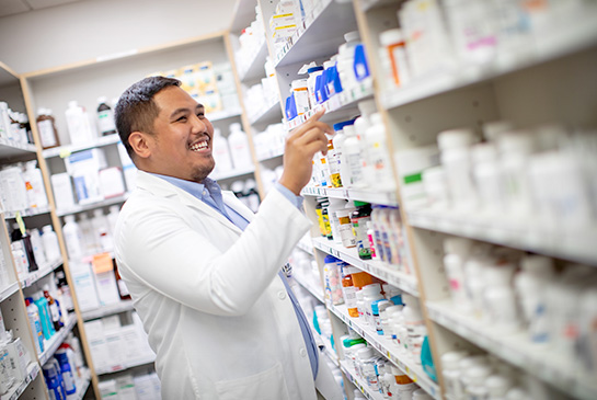 Pharmacist in prescription room, pulling medication from shelf