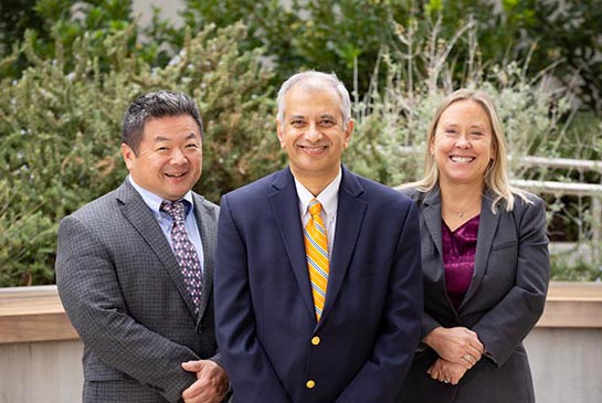 Children's Hospital leaders, 3 doctors pose outside in suits.