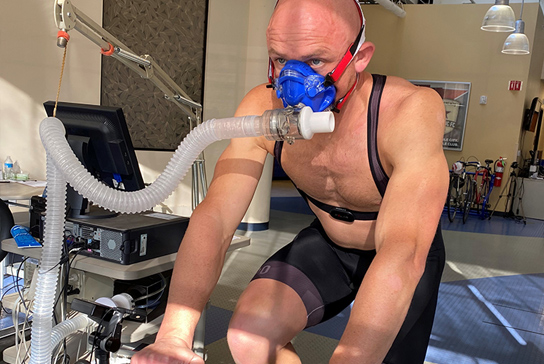 A man walking on a treadmill with a breathing apparatus attached.