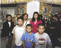 PHOTO -- At his funeral, portraits of Aeng Chang look out over the shoulders of his widow, See Thao, and six of their children