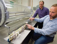 Physicist George Caporaso, standing, and engineer Mark Rhodes, both of Lawrence Livermore National Laboratory, work with a component of the compact proton-beam accelerator they are developing in partnership with UC Davis Cancer Center.
