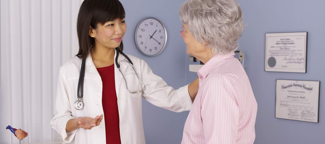 Female Asian physician speaking to older Causasian female