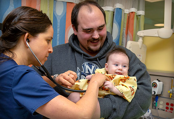 Children's Surgery Center nurse checking vitals of baby being held by father