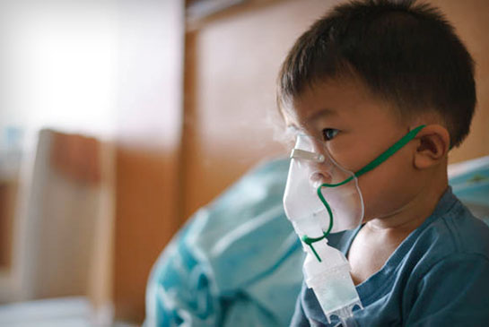 Child with inhaler in hospital room.