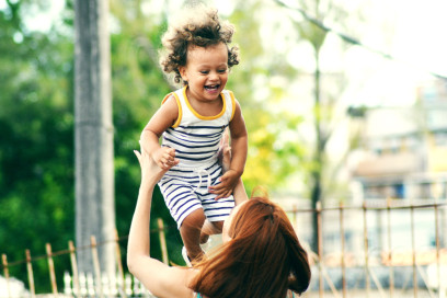Mom lifting laughing baby up in air 
