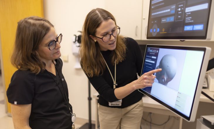 Debra Kahn and Katharine Marder view an image on the transcranial magnetic stimulation device.