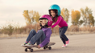 stock image of two girls with helmets on skateboard